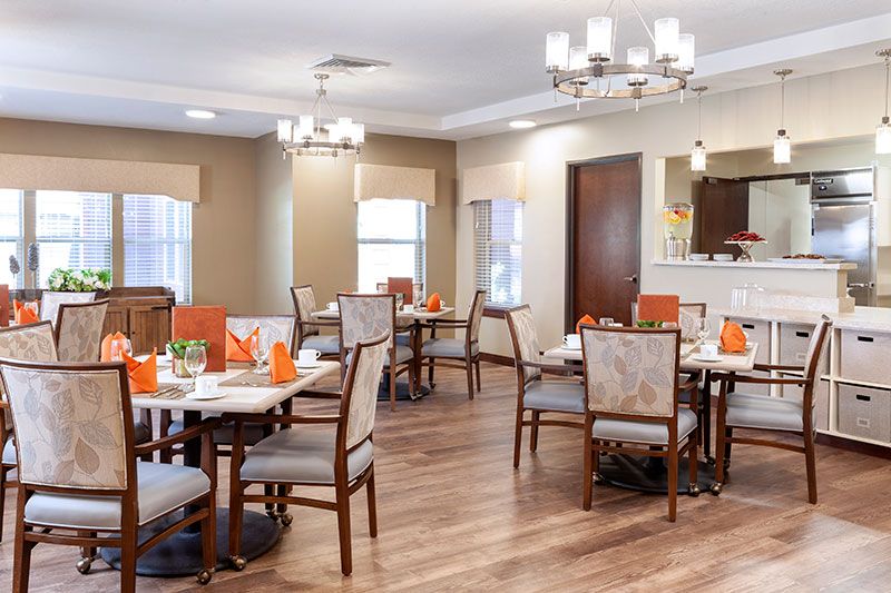 A well-lit dining room with neatly arranged tables and chairs.