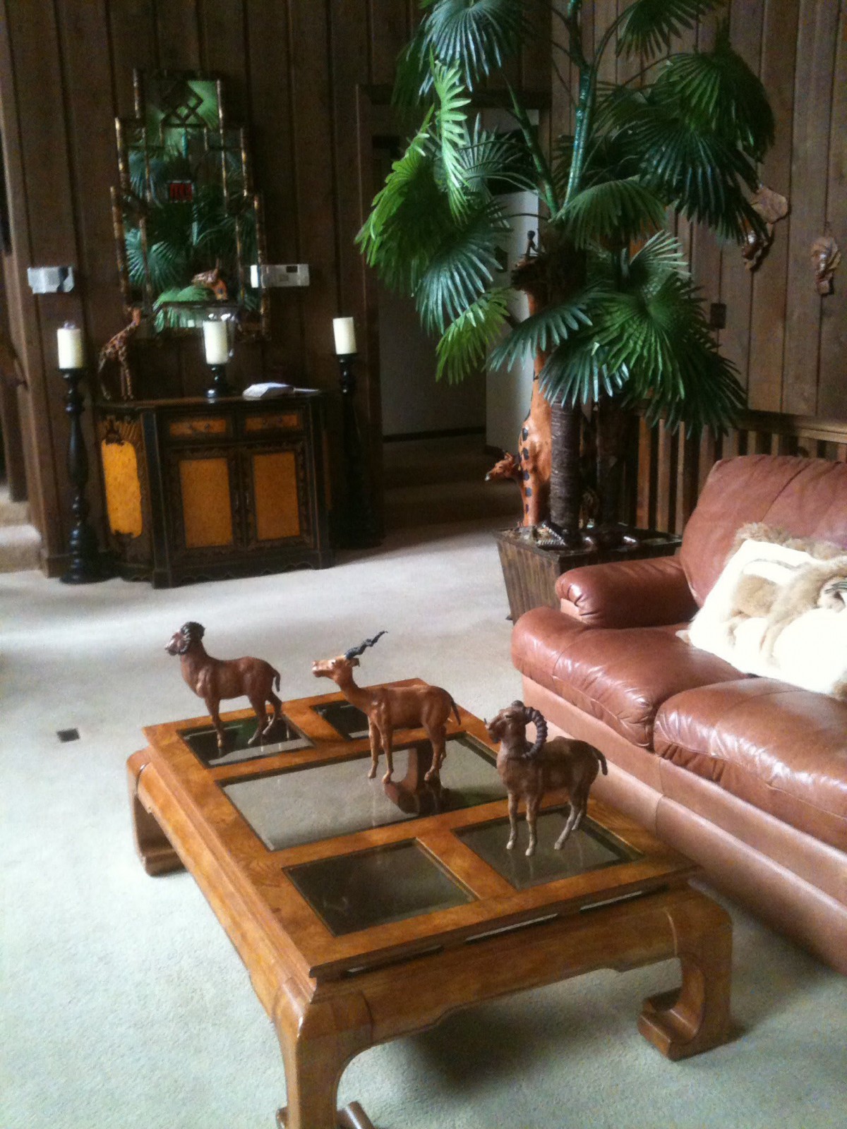 A cozy living room featuring a leather sofa and a wooden coffee table adorned with decorative figurines.