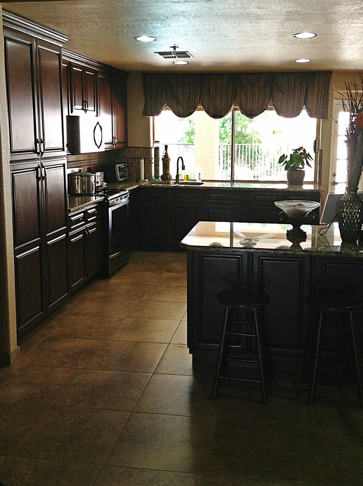 Spacious kitchen with dark cabinets and a large window view.