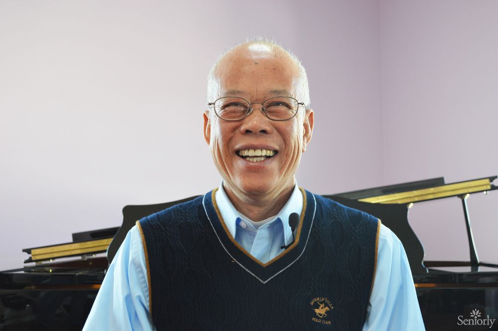 A smiling man wearing a vest and glasses indoors.