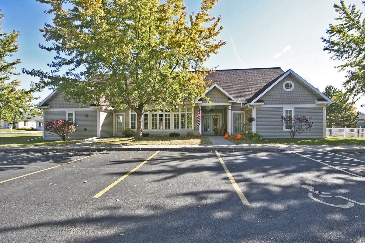A building surrounded by trees and a parking lot in autumn sunlight.