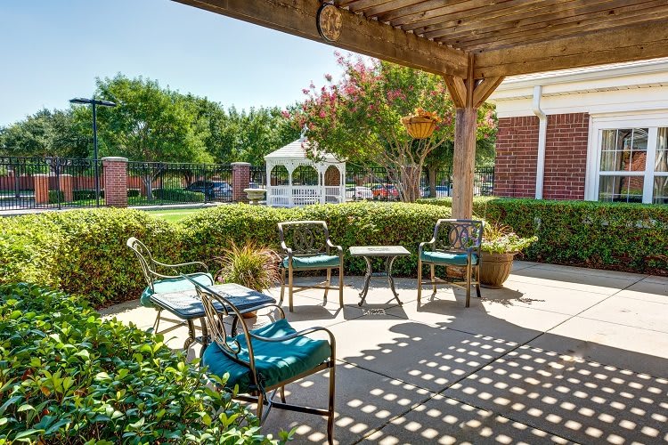 A cozy patio area with outdoor seating and a view of a garden gazebo.