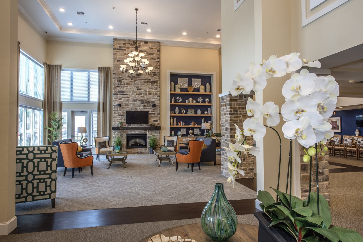 A spacious and elegantly decorated living room featuring a stone fireplace, comfortable seating, and modern decor accents.