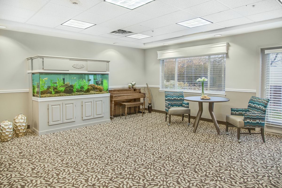 A well-furnished room featuring an aquarium, a table with chairs, and large windows.