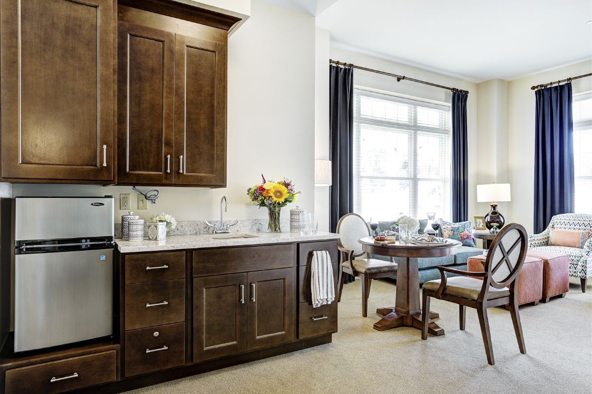 A cozy kitchen with dark wooden cabinets and a dining area featuring a sunflower bouquet.