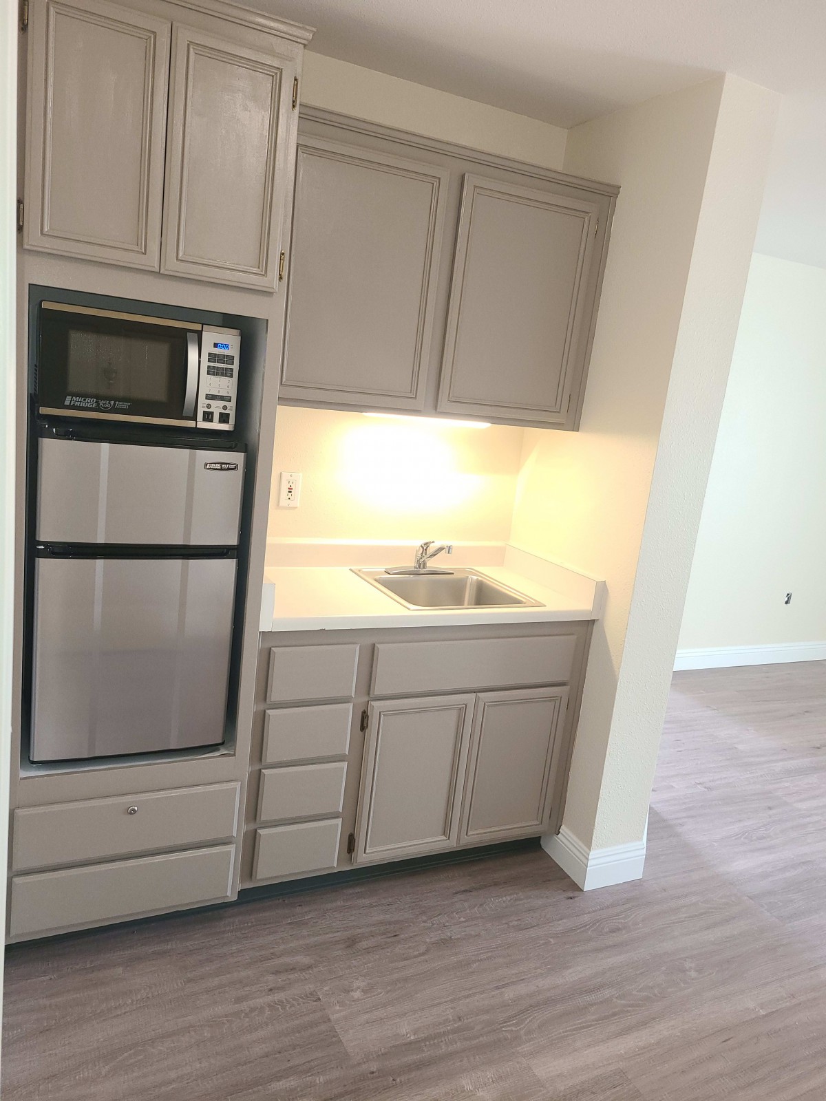 A modern kitchen area with cabinets, an oven, and a sink.
