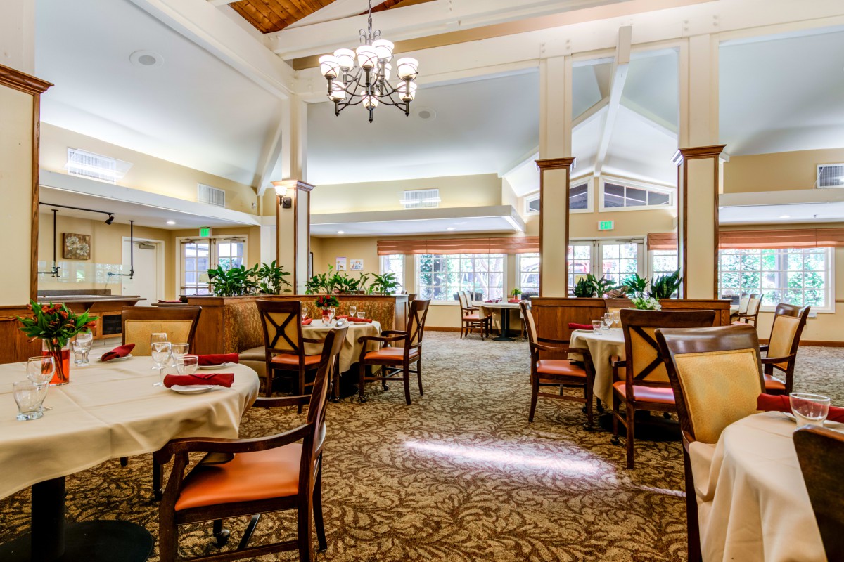 An elegant restaurant dining area with neatly arranged tables and chairs, featuring a chandelier and tasteful decor.