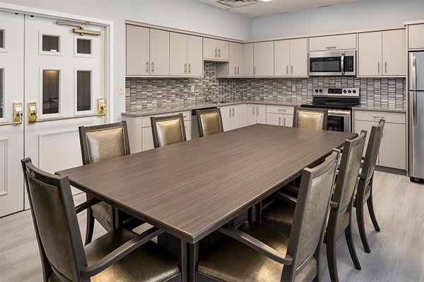 A modern conference room featuring a large meeting table and adjacent kitchen area.