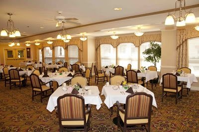 An elegant dining room with neatly arranged tables and chairs, well-lit by overhead lamps, creating a cozy atmosphere.