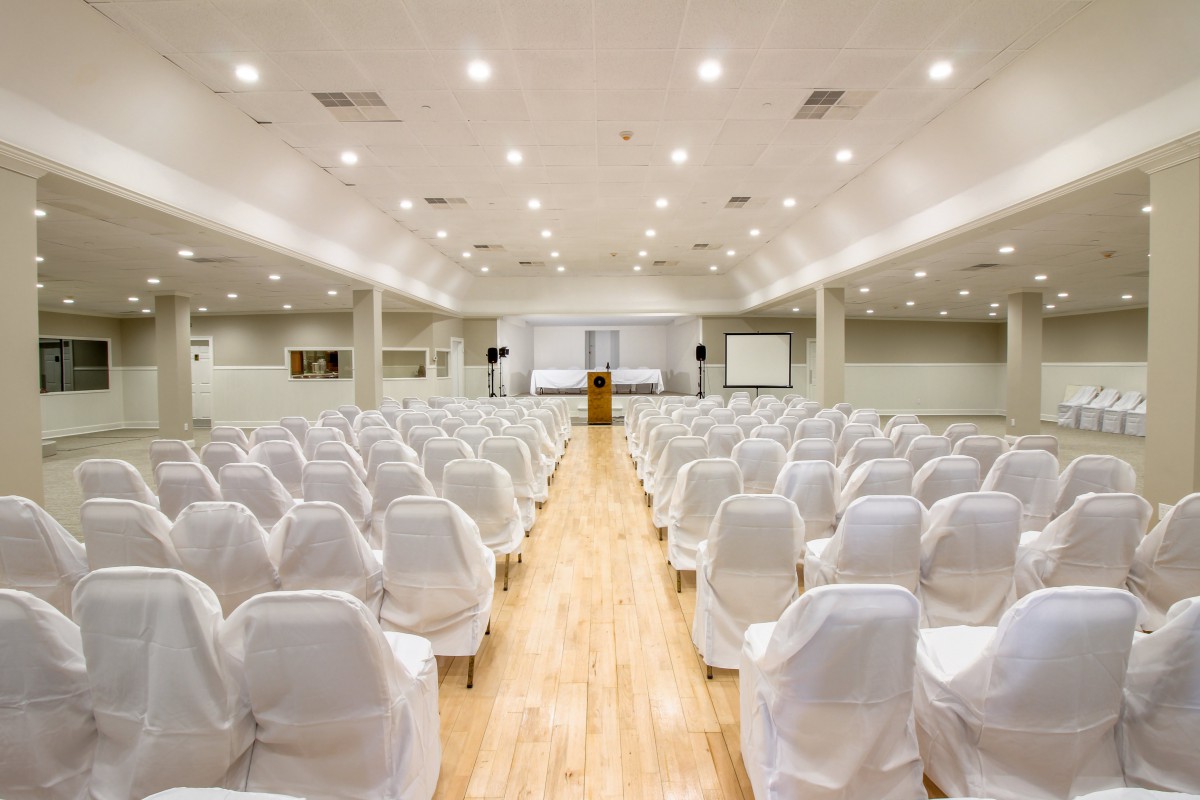 Empty conference room with white-covered chairs and a central podium.