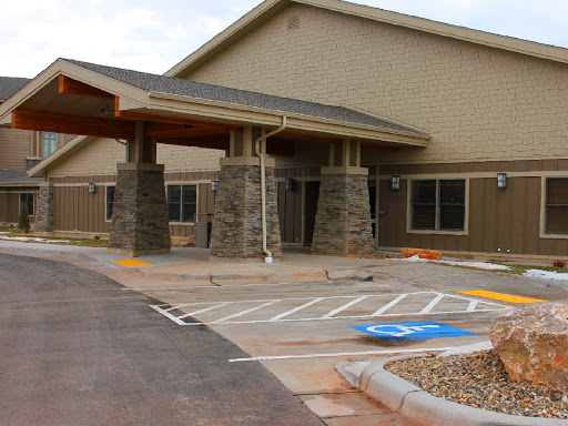 A modern building entrance with stone accents and a parking area.