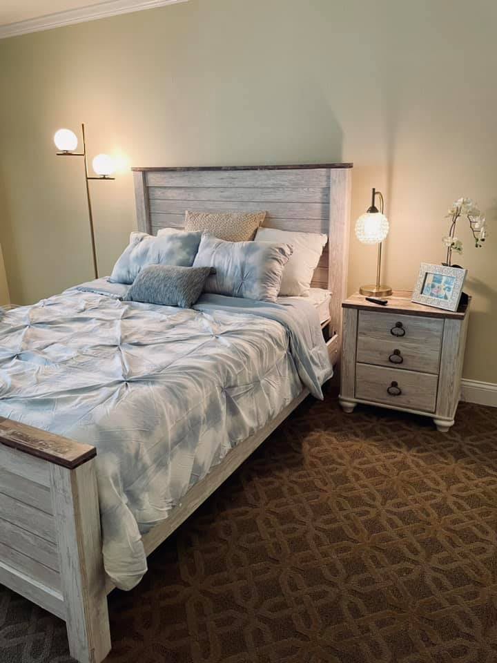 A cozy bedroom with a neatly made bed and a stylish nightstand featuring decorative lamps.