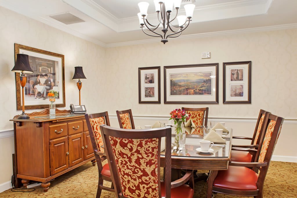 An elegant dining room featuring a chandelier, ornate chairs, and a beautifully set table.