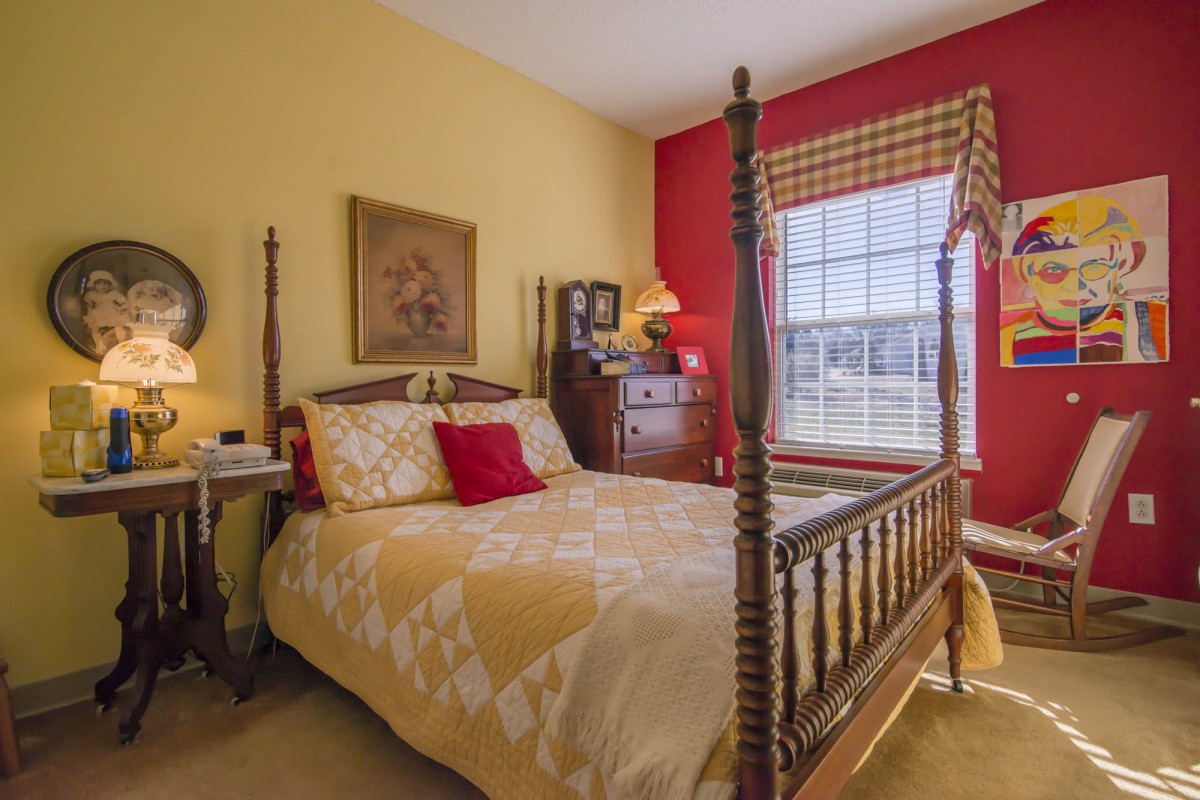 A traditional bedroom with red and yellow walls, featuring a wooden bed and classic furniture.