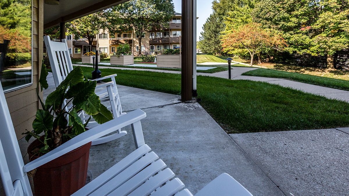 A peaceful porch with white chairs overlooking a green garden and pathway.