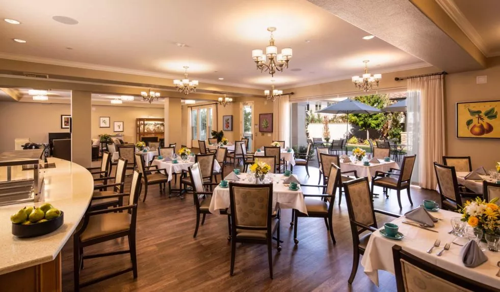 An elegant dining room with neatly arranged tables and chairs, adorned with chandeliers.