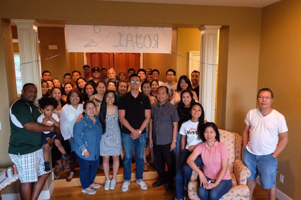 A large group of people gathered indoors for a celebration, posing in front of a banner.