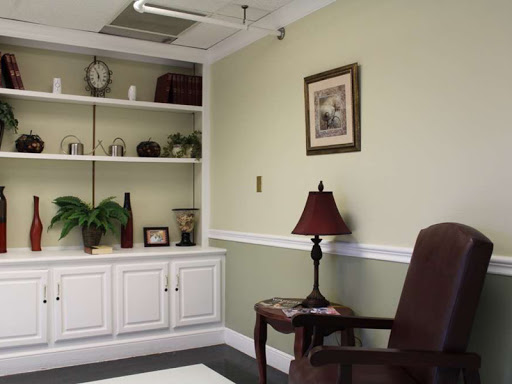 A cozy office space featuring a green wall, shelves filled with decor, and a comfortable chair.