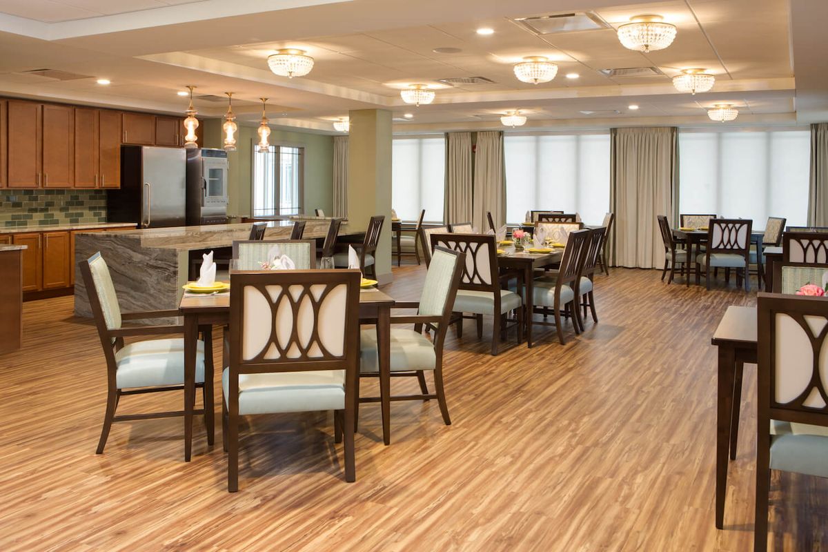A spacious and elegantly furnished dining area with wooden flooring and stylish lighting fixtures.