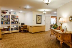 A well-lit reception area with a desk, bookshelf, and computer.