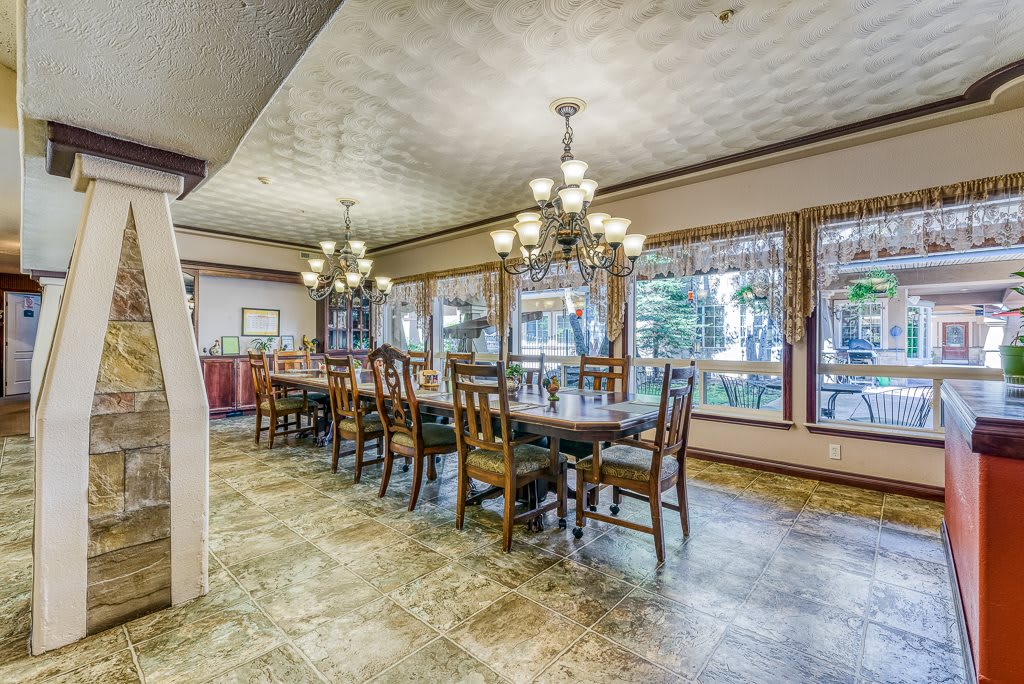 A spacious dining room with large windows and elegant chandeliers.