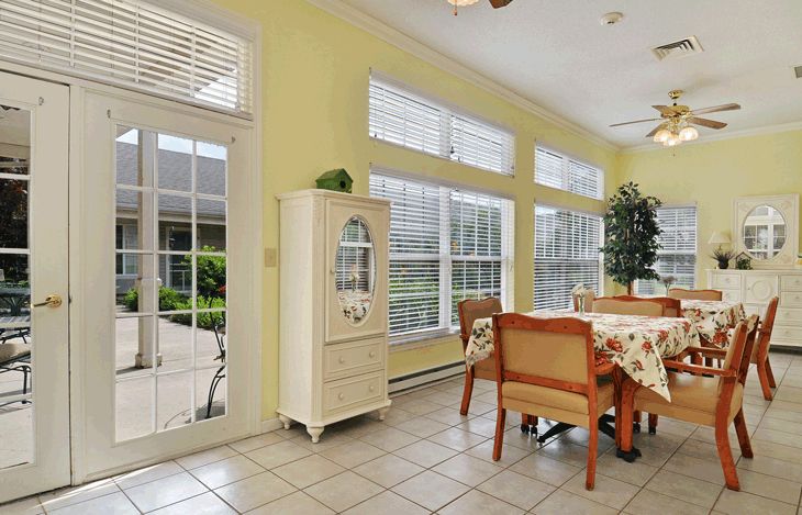 A bright dining room interior with large windows and wooden furniture.