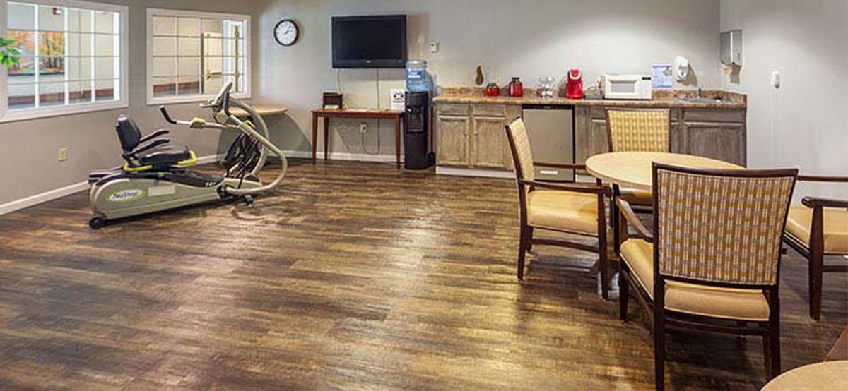 A cozy room with exercise equipment, seating area, and a kitchenette.