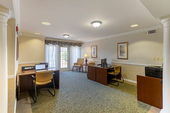 A well-lit office interior featuring multiple workstations with computers and chairs, complemented by decor and ample natural light.