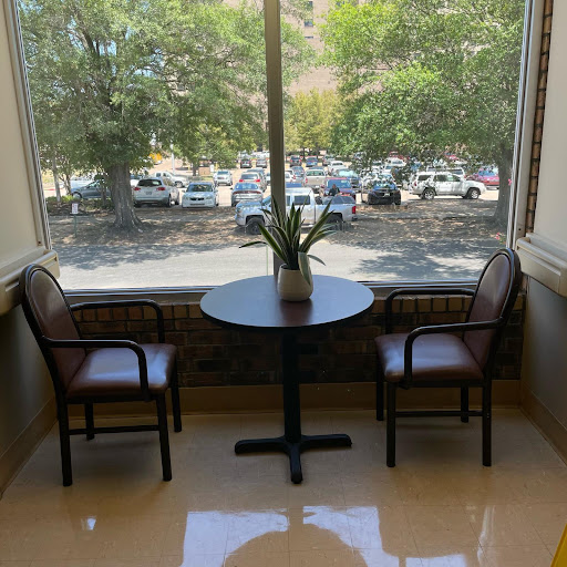 A cozy seating area by the window, featuring a table and two chairs with a plant centerpiece.