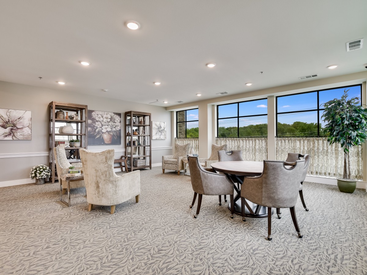 A spacious and elegantly decorated living room with large windows, featuring comfortable seating and a central table.