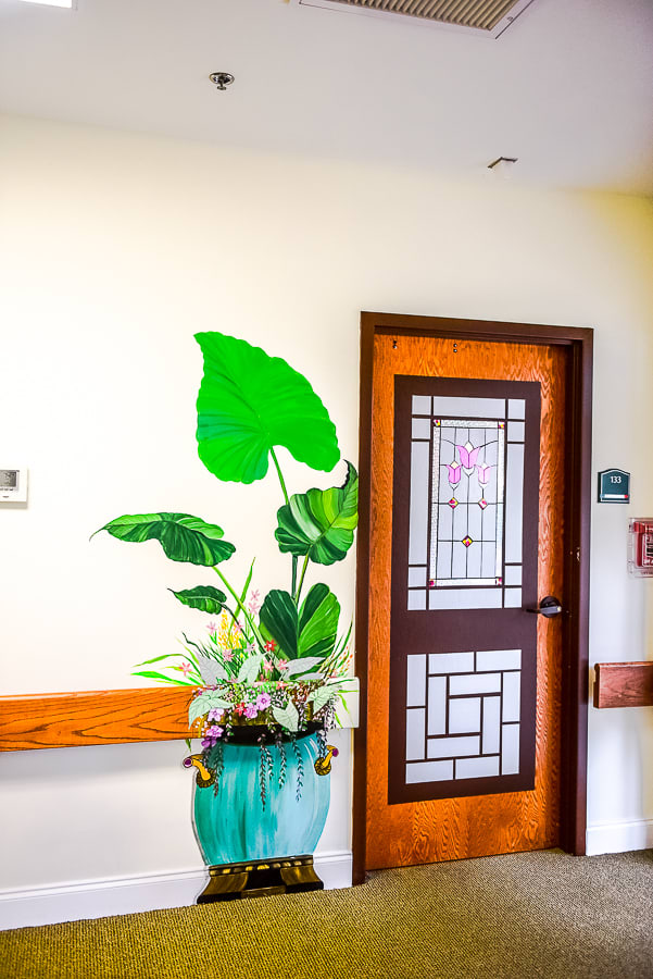 A hallway with a potted plant beside a decorative door.