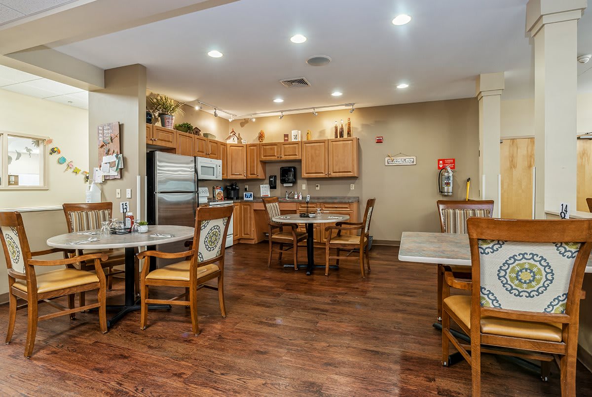 A cozy kitchen and dining area with wooden floors, tables, and chairs, featuring modern appliances and cabinets.