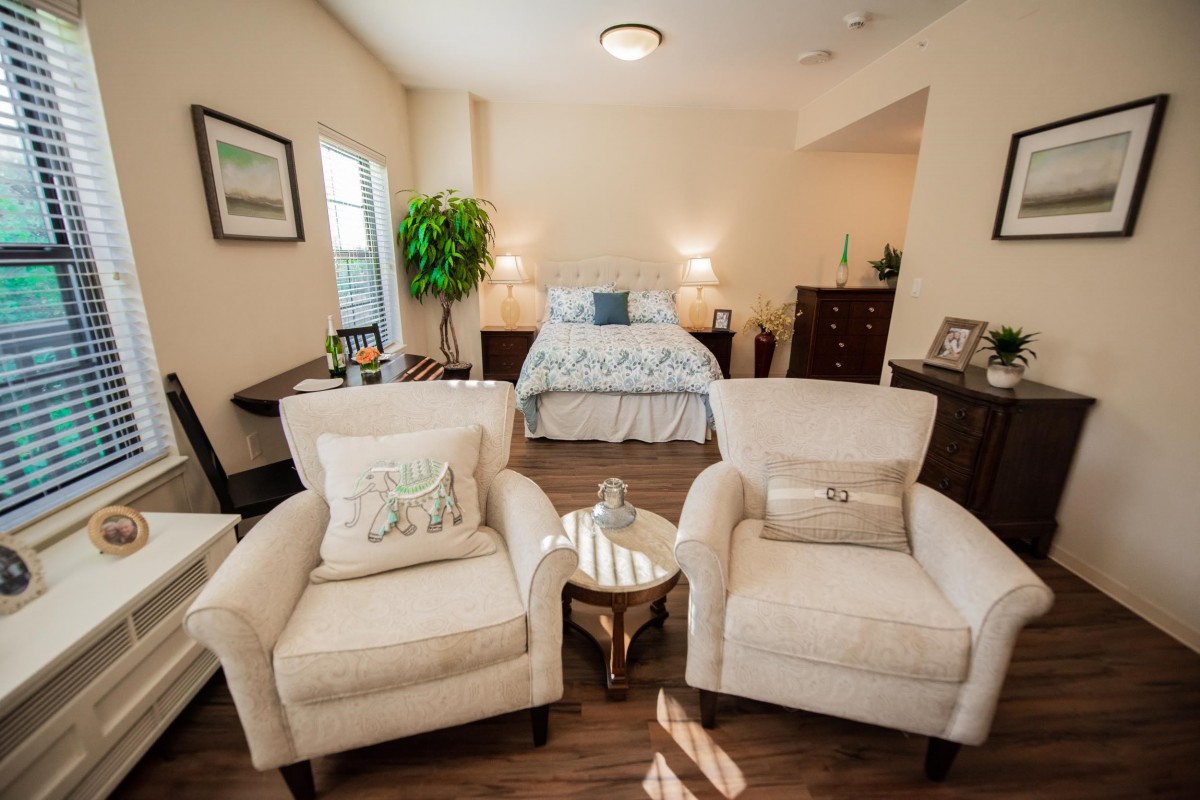 A cozy bedroom with two armchairs, a bed, and elegant decor.