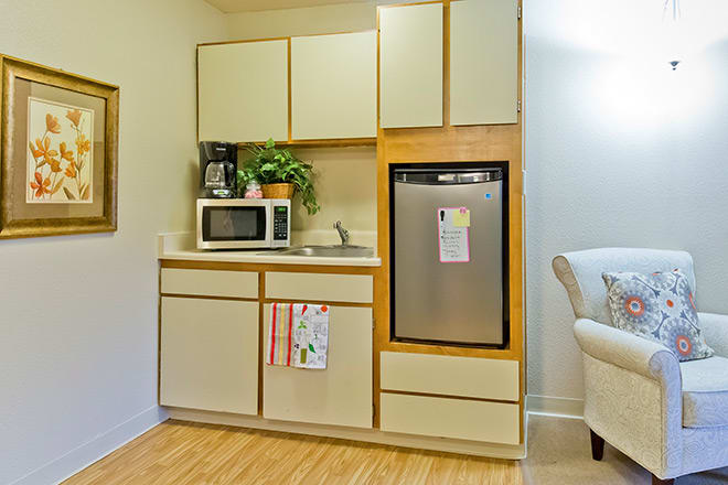 A compact kitchen featuring appliances like a microwave and refrigerator, along with a coffee maker and houseplant on the countertop.