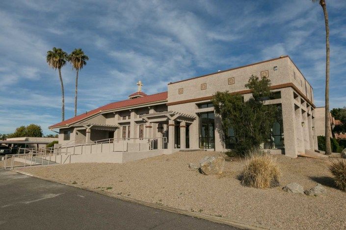 A desert building with architectural columns and palm trees under a blue sky.