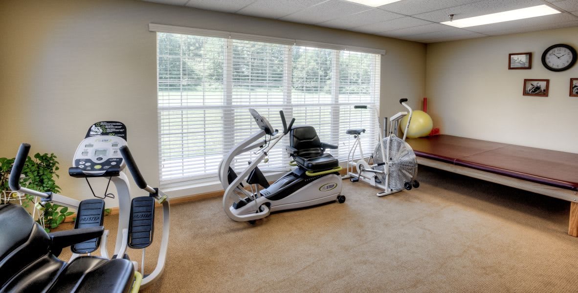 A bright gym with various exercise equipment and large windows.