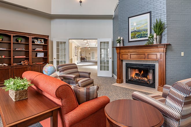 A cozy living room featuring a fireplace, comfortable armchairs, and wooden shelves.