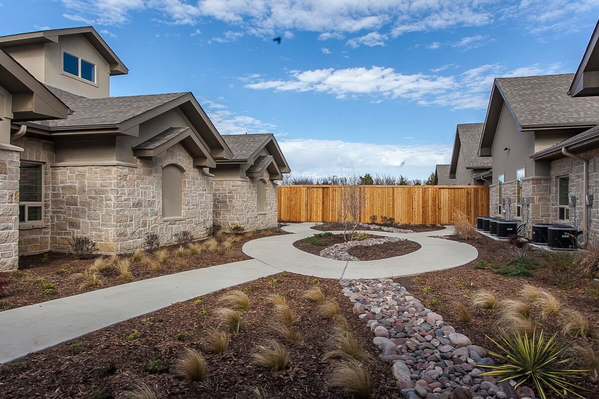A modern suburban home with landscaped pathway and wooden fencing.