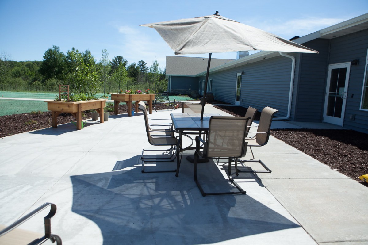 A sunny outdoor patio with a table, chairs, and an umbrella.