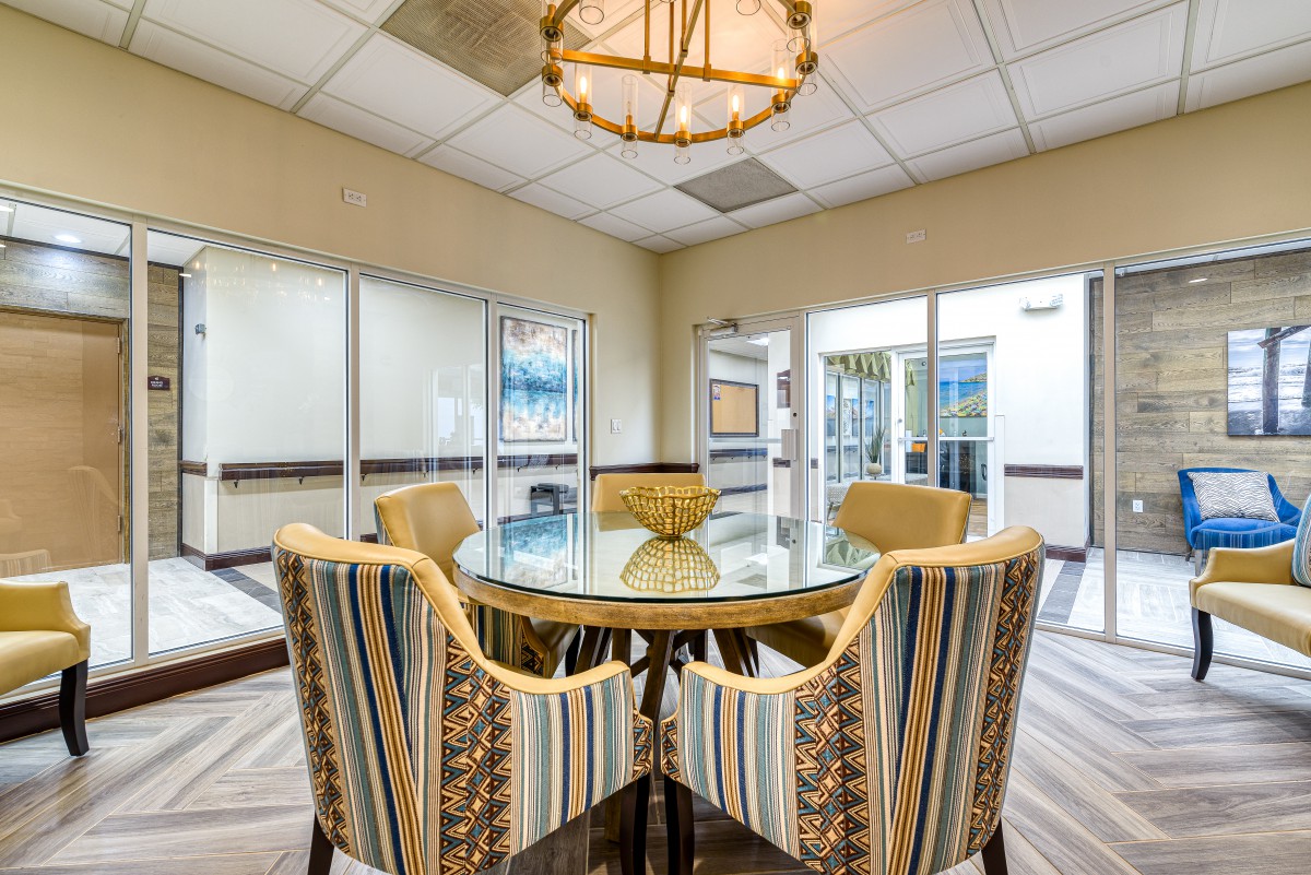 A modern conference room featuring a glass table and striped chairs under a stylish chandelier.