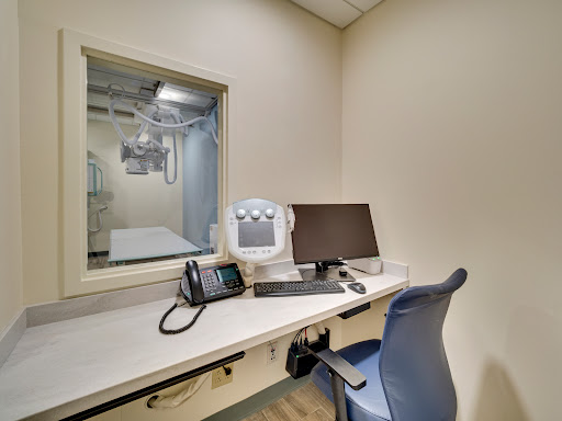 A view of a medical office workspace, featuring a desk with a computer and phone.