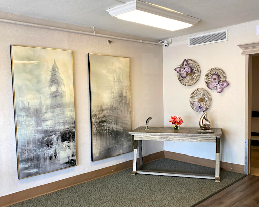 A modern interior space featuring large abstract paintings, decorative plates on the wall, and a stylish desk with a flower arrangement.