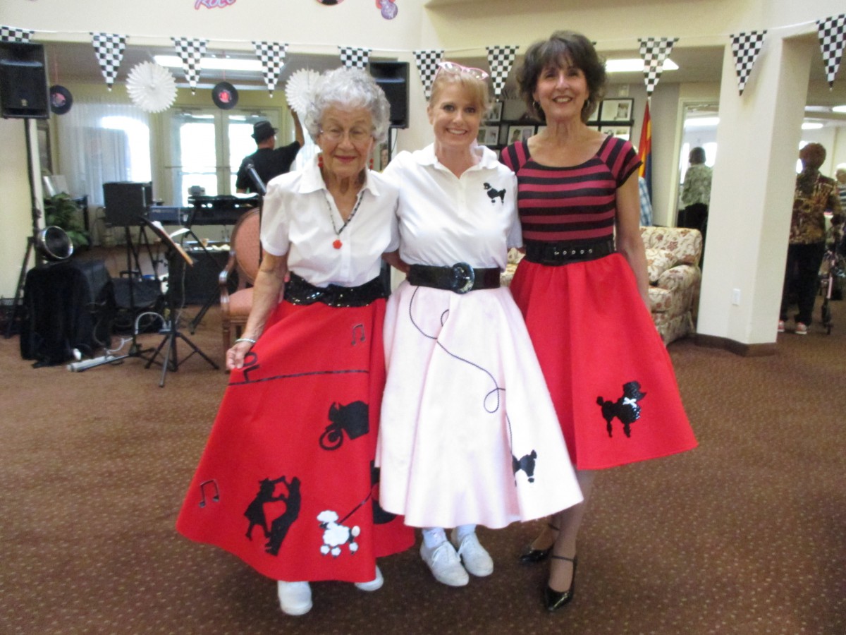 Three women wearing vintage-style poodle skirts, reminiscent of 1950s fashion.