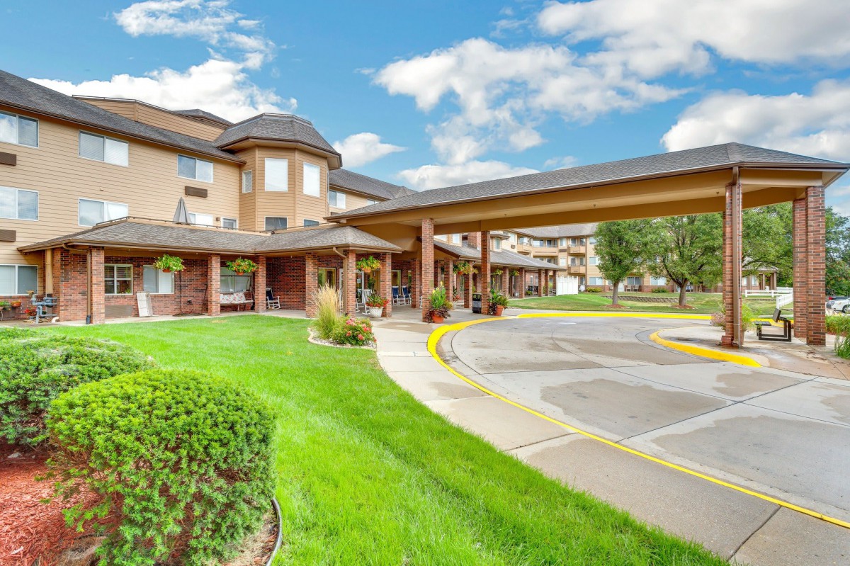 A scenic view of a hotel building with lush greenery and a bright blue sky.