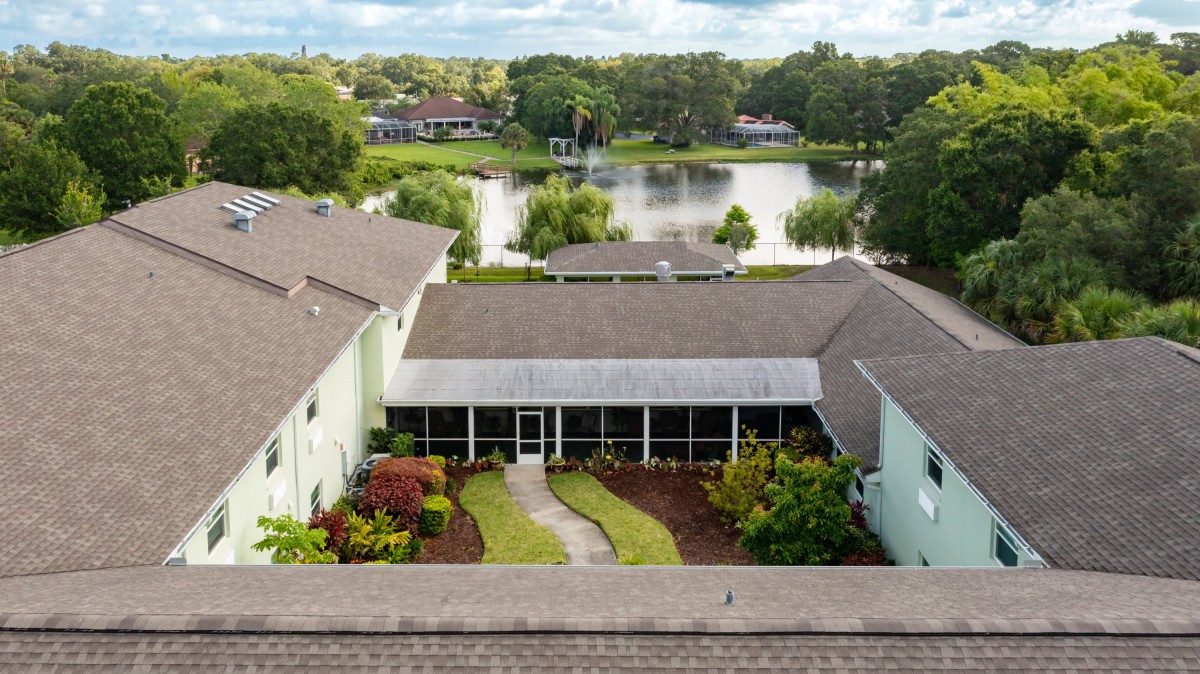 Aerial view of a residential house with a well-kept backyard garden and a scenic lake in the background.