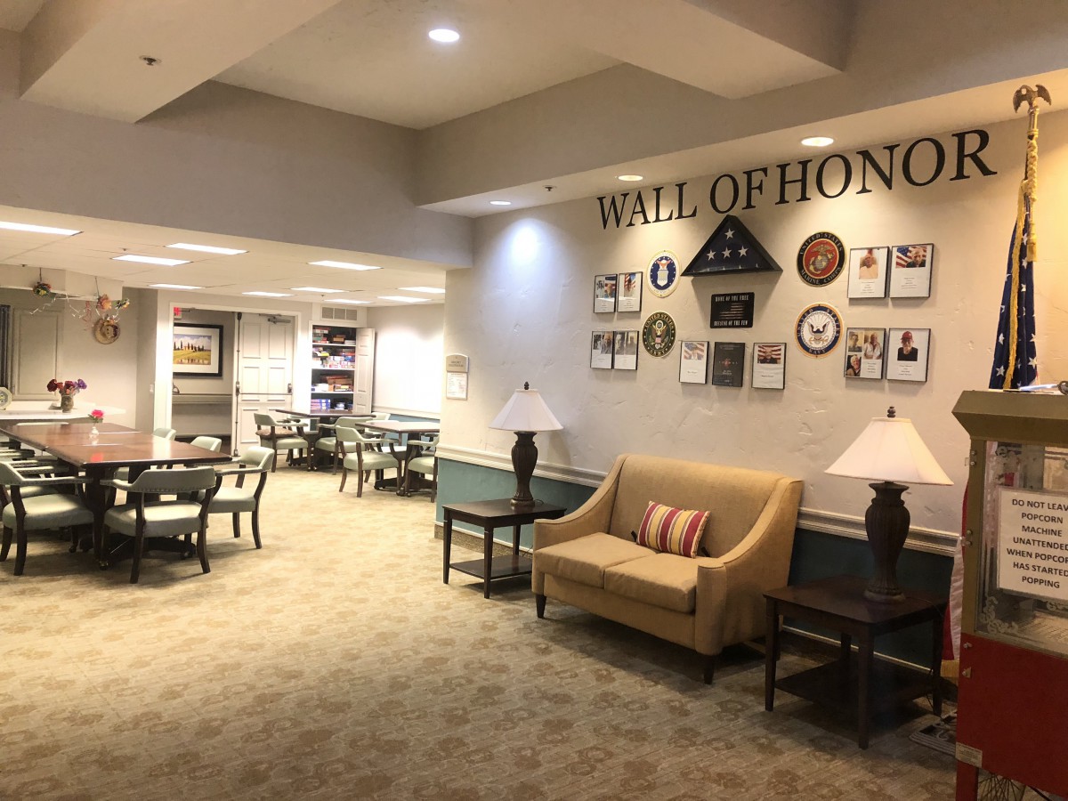 A comfortable lounge area featuring a 'Wall of Honor' adorned with plaques and awards, along with seating options including sofas, tables, and chairs.