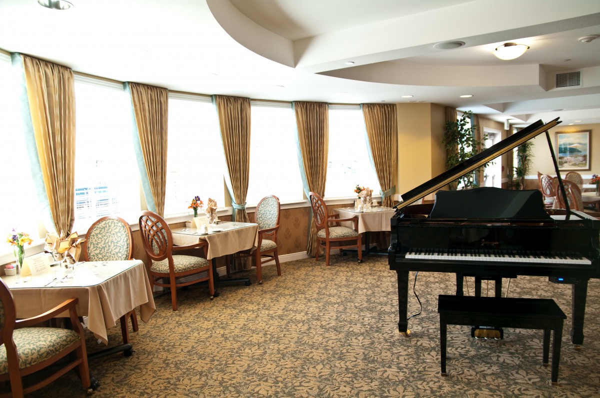 Elegant dining area featuring a grand piano with tables and seating.