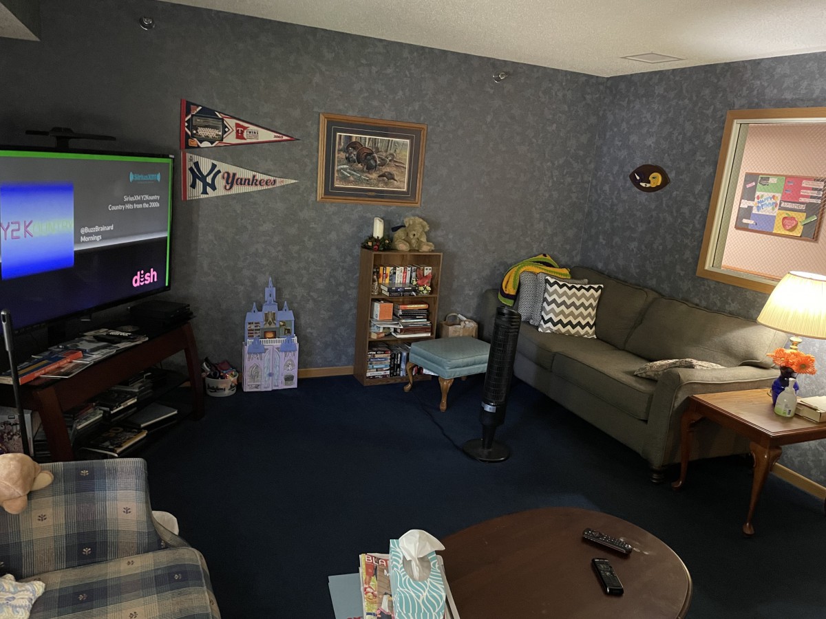 A cozy living room with a TV, couch, and various decorations including pennants and wall art.