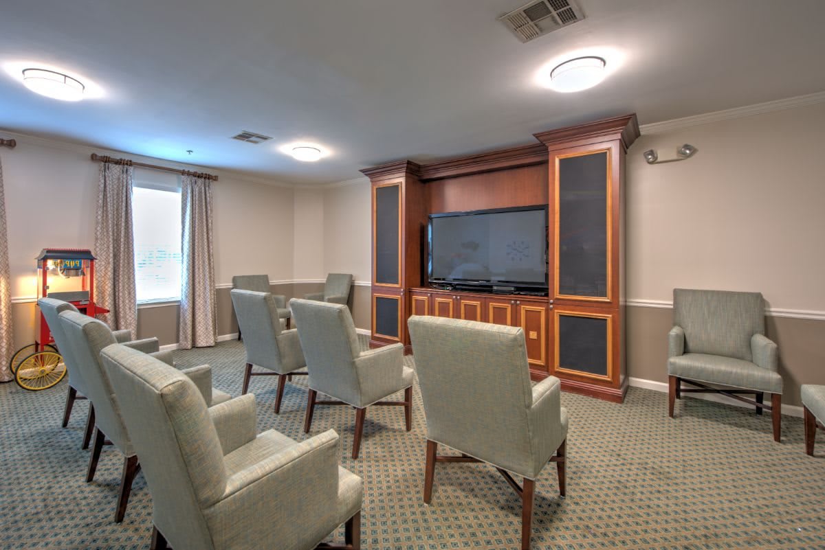 A small conference room with chairs arranged around a large television.