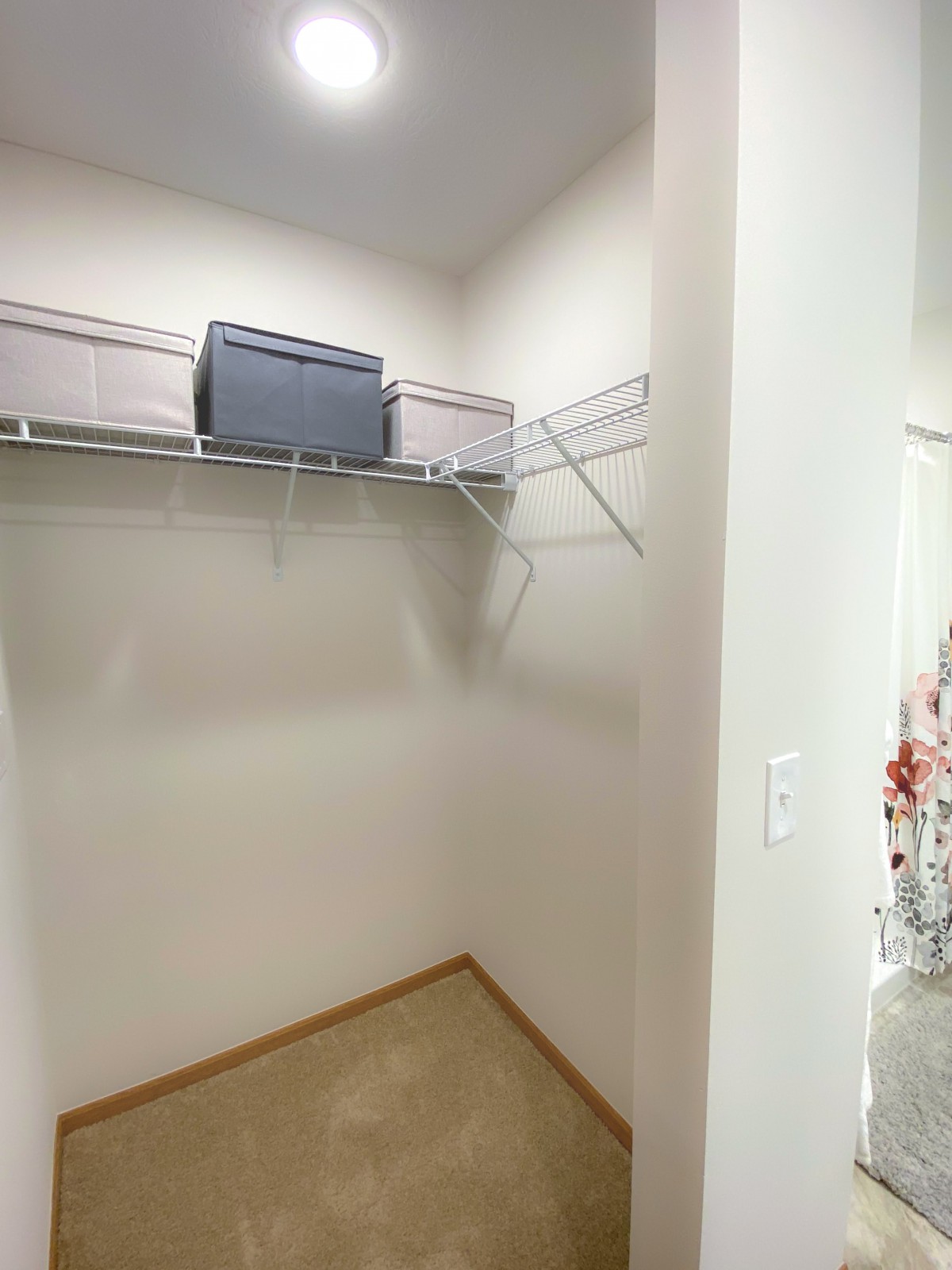 An empty closet with a wire shelf and minimal storage.